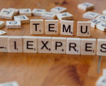Scrabble tiles spelling the word temu allexpress on a wooden table