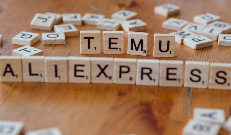 Scrabble tiles spelling the word temu allexpress on a wooden table