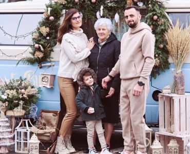 A multi-generational family posing with festive Christmas decorations outside a decorated van.