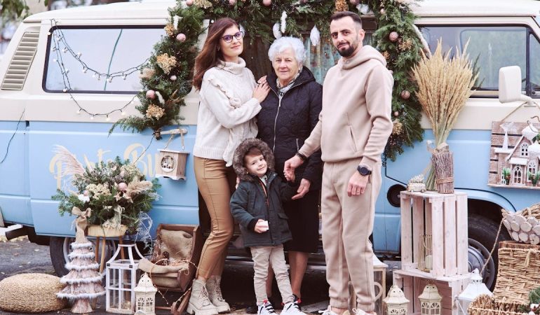 A multi-generational family posing with festive Christmas decorations outside a decorated van.