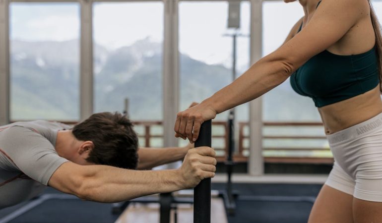 A couple working out together at an indoor gym with mountain views.