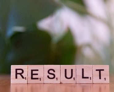 A wooden block spelling the word result on a table