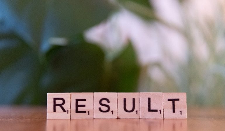 A wooden block spelling the word result on a table